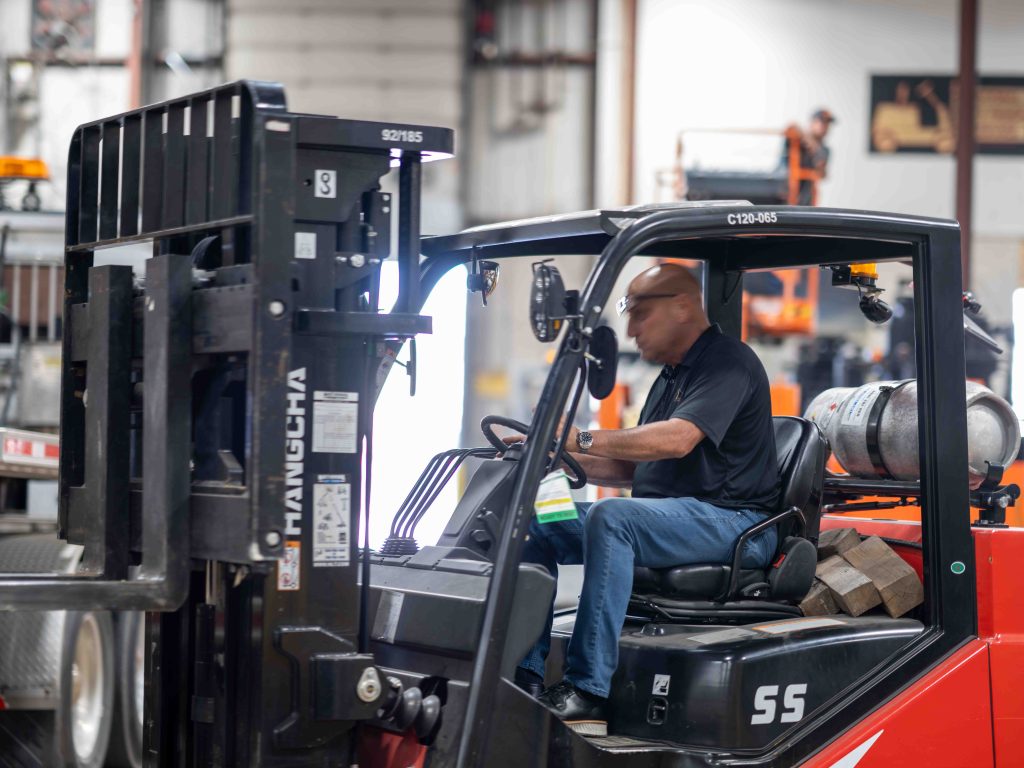 man driving a forklift through a shop