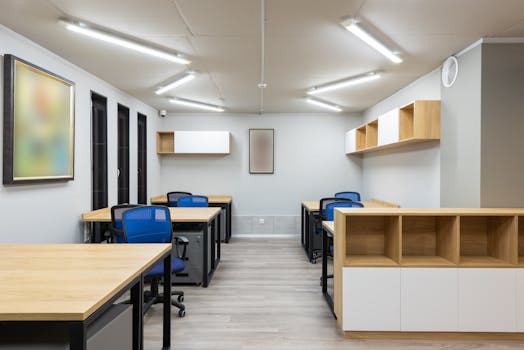 Interior of contemporary workspace with office chairs at tables and wooden shelves under ceiling with geometric lamps